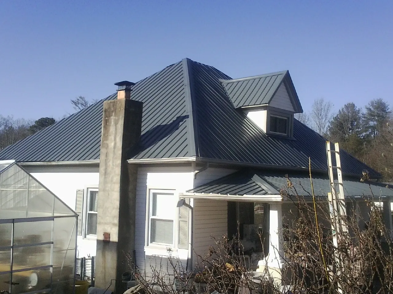 Dark blue standing seam metal roof on a white farmhouse with dormer — Slate & Tile Roof Repair by Roofing Brothers in New Ellenton