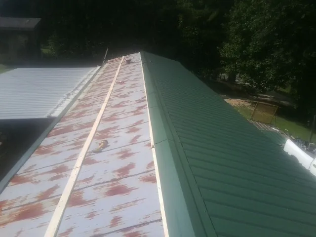 Old rusted panels beside newly installed green metal roofing — Wind Damage Roof Repair by Roofing Brothers in New Ellenton