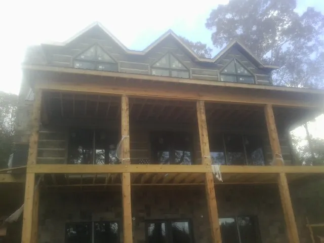 Dormers and porch framing on a large log home under construction — Roof Coating work by our crew in New Ellenton