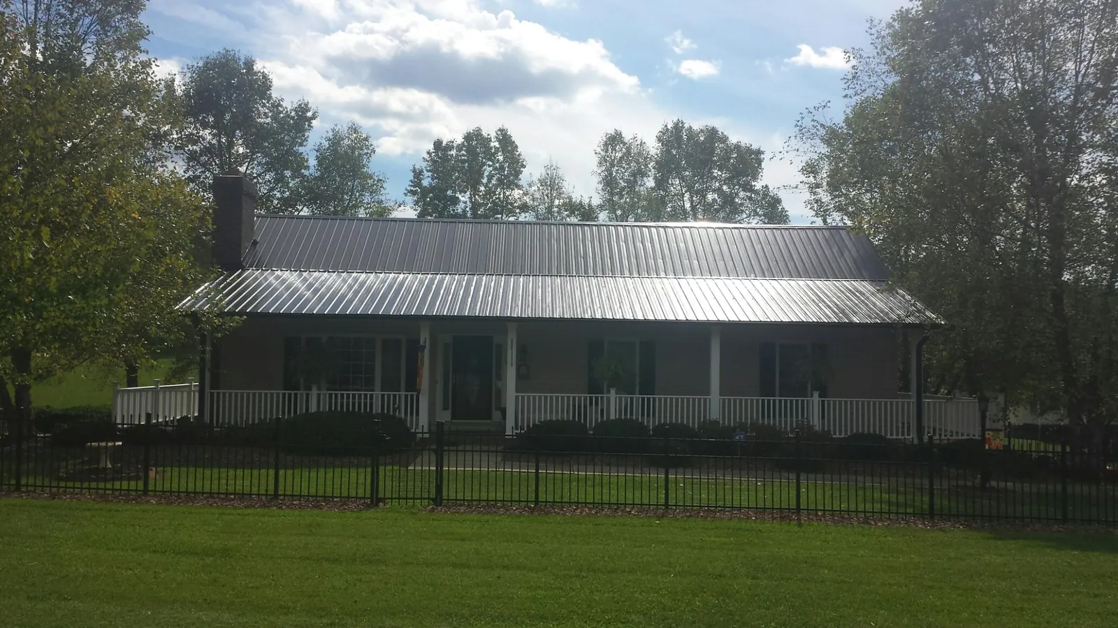 Gray metal roof on a brick ranch with a full width front porch — Gutter Guard Installation work by our crew in New Ellenton