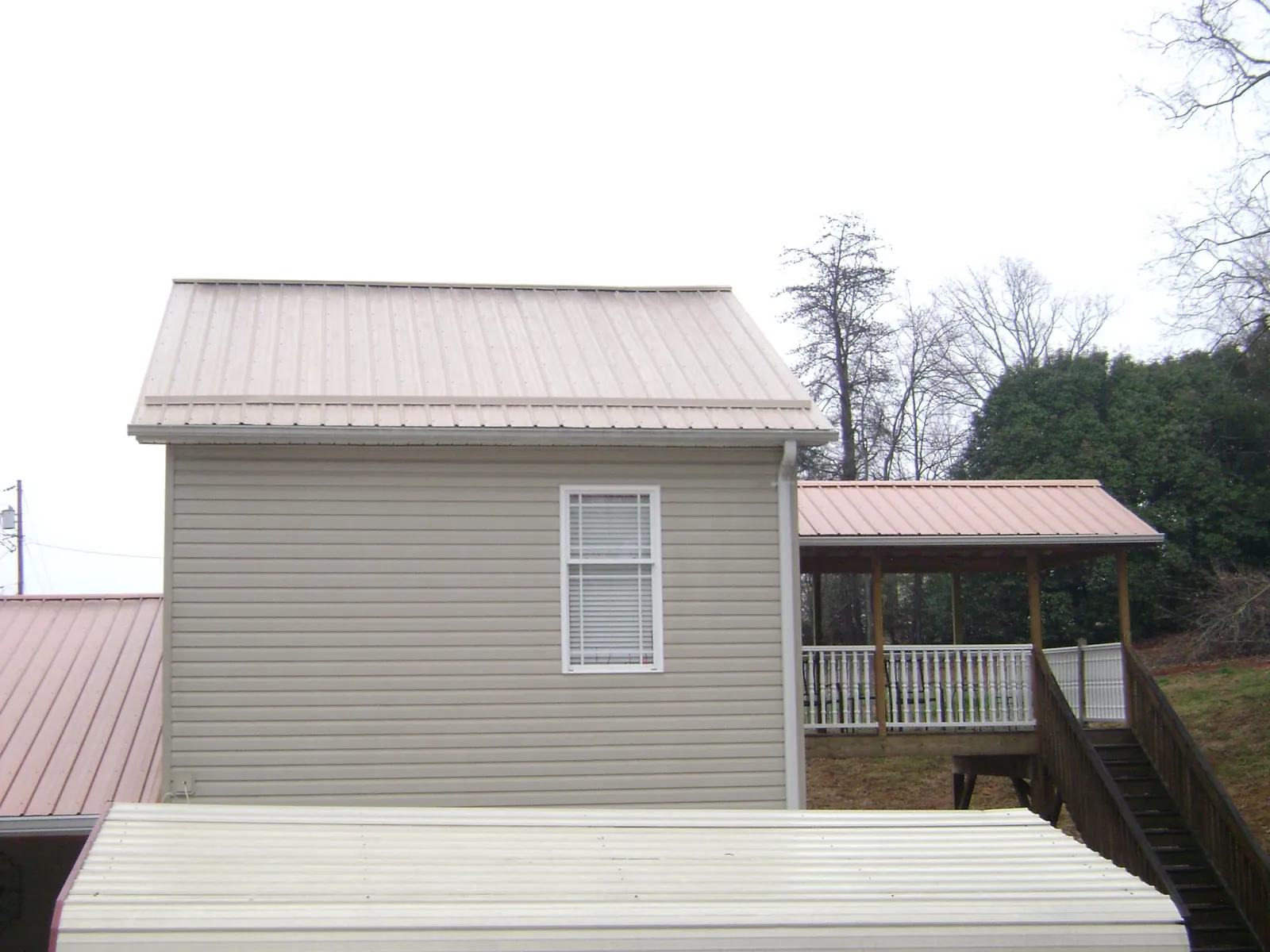 Tan metal roofs on a two story addition and attached porch, from a Roof Replacement job in New Ellenton